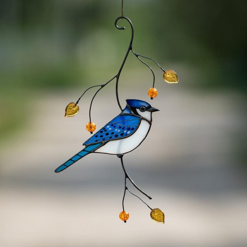 Hangende blauwe gaai van gekleurd glas aan een metalen tak met amberkleurige blaadjes en kraaltjes