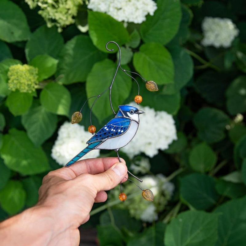 De vogeldecoratie wordt vastgehouden voor een hortensiastruik