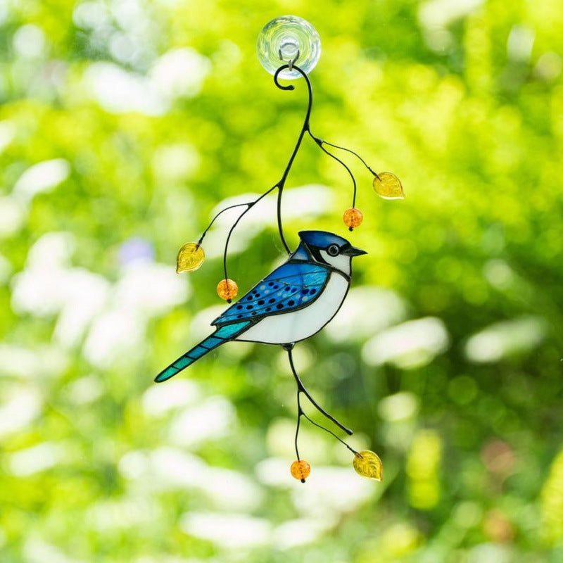 De vogeldecoratie hangt voor een raam met groen en witte bloemen op de achtergrond